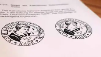 Zwei Siegel des Katholischen Datenschutzzentrums mit dem Schriftzug 'Kath. Datenschutzzentrum' und einer abgebildeten Person, die einen Stift hält.